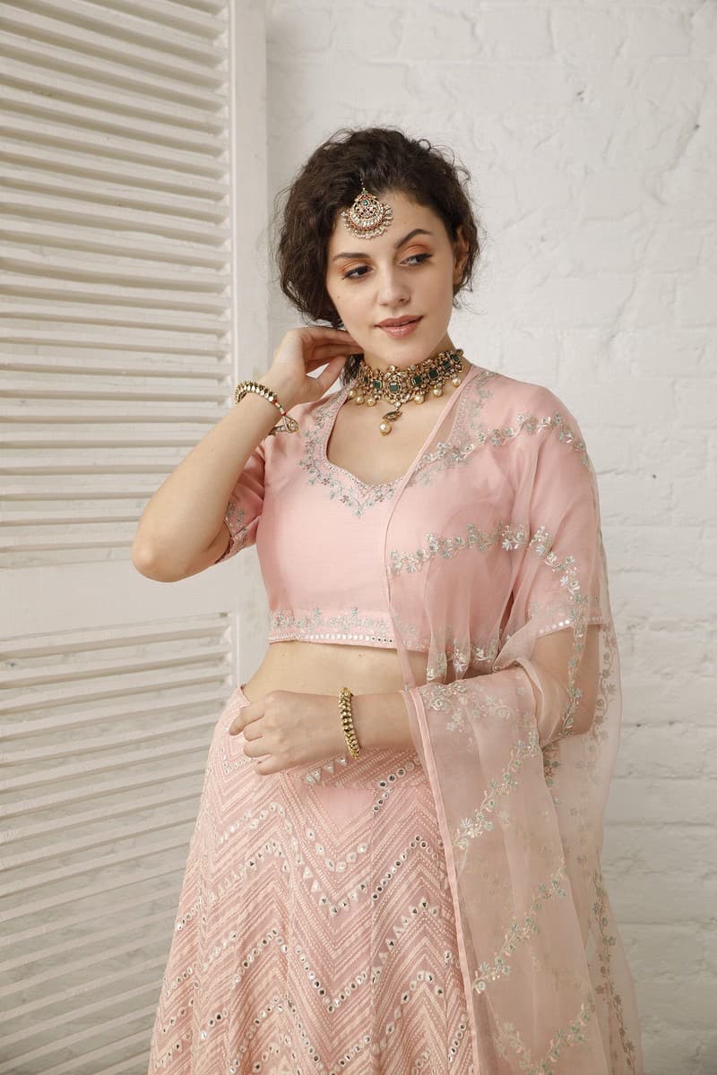 Photo of Pretty bride in pastel pink lehenga with gold jewellery